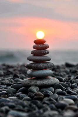 Foto keren matahari sedang berada di ujung batu Foto keren batu di pinggir pantai yang menyala