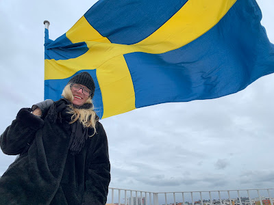 Leende Lotta Löfwall och en svensk flagga i bakgrunden