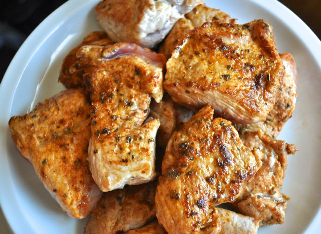 cooked carnitas meat with seasoning on top stacked on white plate