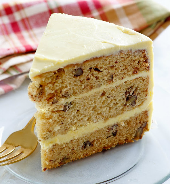 This lovely cake is the perfect combination of flavors and textures. The warm maple syrup blends perfectly with pecans for an out of this world cake, the maple frosting is amazing too! Dessert is served and it's delicious! slice of triple layer cake studded with nuts and smooth frosting