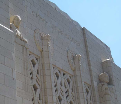 White exterior above the west doors, engraved Omaha Union Station, with two flanking sculptural figures