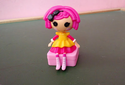 Brinquedo de plástico, mini boneca lalaloopsy rosa sentada sobre uma caixa   R$ 15,00