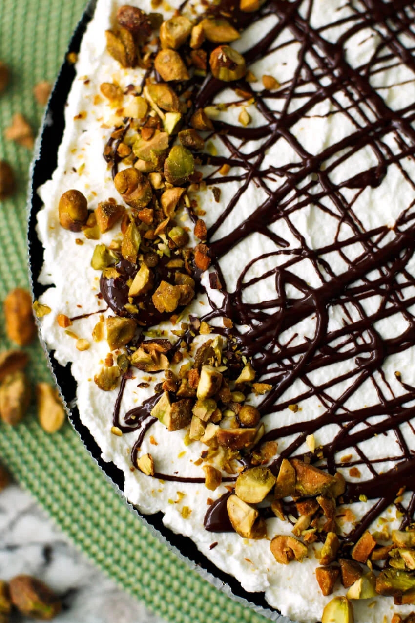 This Pistachio Pudding Pie is a no-bake dessert with an Oreo cookie crust, a creamy pistachio filling, fresh whipped cream, and a pretty chocolate drizzle. It is perfect for parties and picnics!  #nobake #pie #dessert