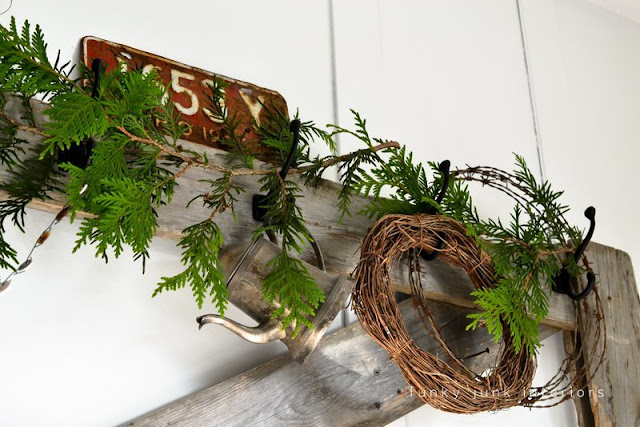 A Christmas decorated headboard with an evergreen and button garland via Funky Junk Interiors