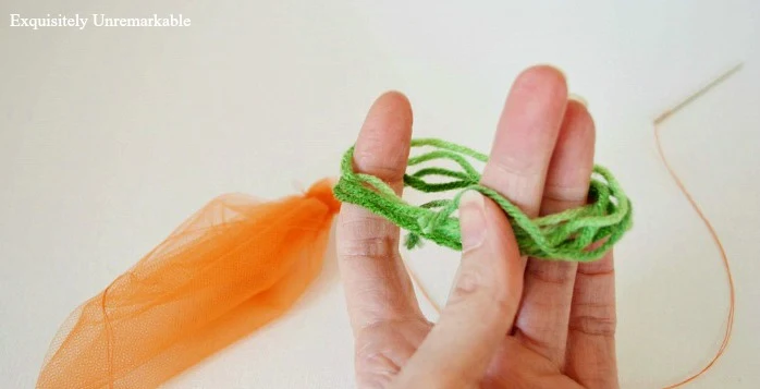 Winding green yard around fingers to make leaves for carrot garland