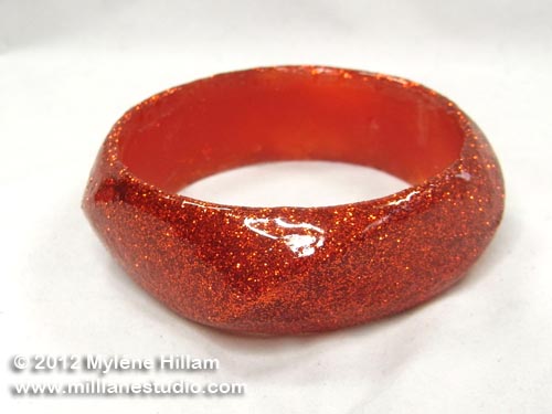 Resin bangle covered with pumpkin coloured glitter