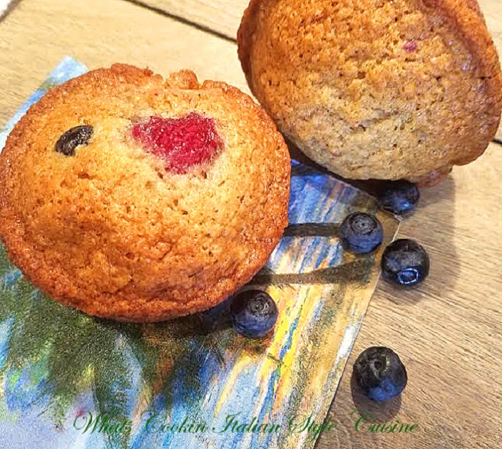 these are Summer Berry Muffins are a quick bread with banana, raspberries and blueberries. Golden brown sweet muffins with fresh fruits and on a tropical palm tree plate