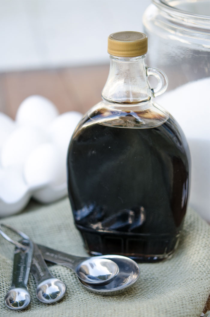 An empty raspberry syrup bottle is repurposed for holding vanilla in the kitchen.  Find more useful glass storage ideas #organize #storage #repurpose #andersonandgrant