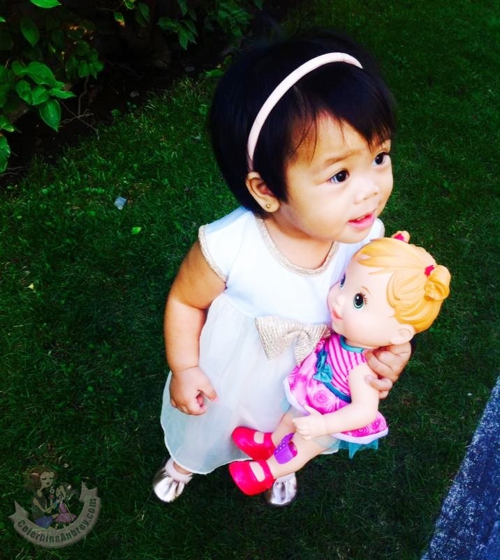 Baby girl on a white dress with her Baby Alive Doll