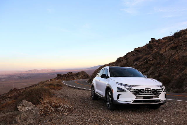 Creme-weisser Hyundai Nexo mit futuristischer Frontpartie in der Bergkurve