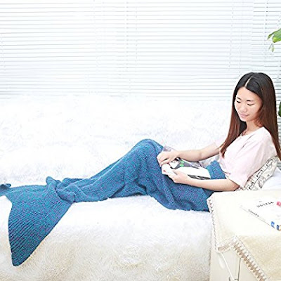 woman modelling a blue sleeping bag-style blanket shaped like a mermaid's tail