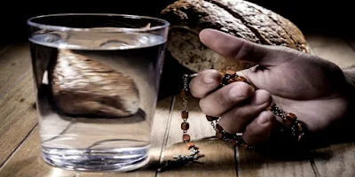 imagem de um copo de água, um pão e terço