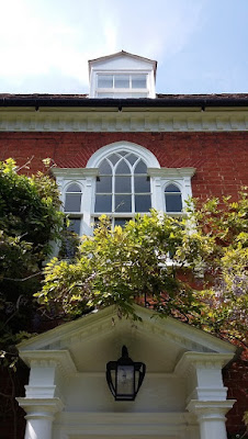 Picture of the front door to our new house since moving to the country, covered in wisteria, and the windows on the two storeys above.