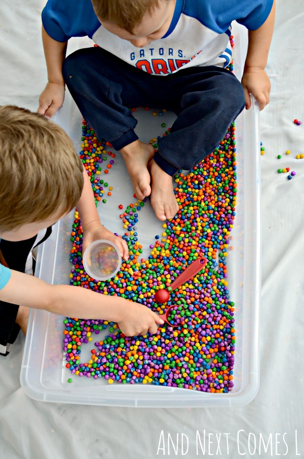 Playing with rainbow dyed dried chickpeas - a great sensory bin filler for toddlers and preschoolers from And Next Comes L