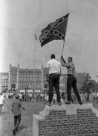 Two people raising flags on Woodlawn high school board
