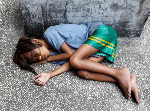 Street child sleeping on sidewalk in the Philippines