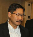A middle-aged Korean man with eyeglasses and a mustache