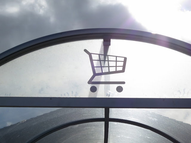 Sign above covered place for trolleys in supermarket carpark.