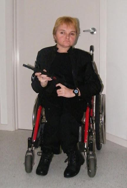 Kellie, in a wheelchair, dressed up in a costume, holding a gun