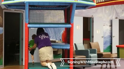 Cafe O'Play staff member helps child climb steps of two story play structure