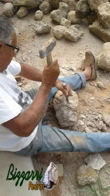 Bizzarri trabalhando, fazendo o corte das pedras moledo para fazer o revestimento de pedra na parede, com pedra moledo na cor bege com espessura de 15 a 20 cm.