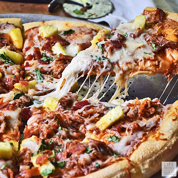 BBQ Pulled Pork Pizza - pulling a slice of pizza with cheese stretching
