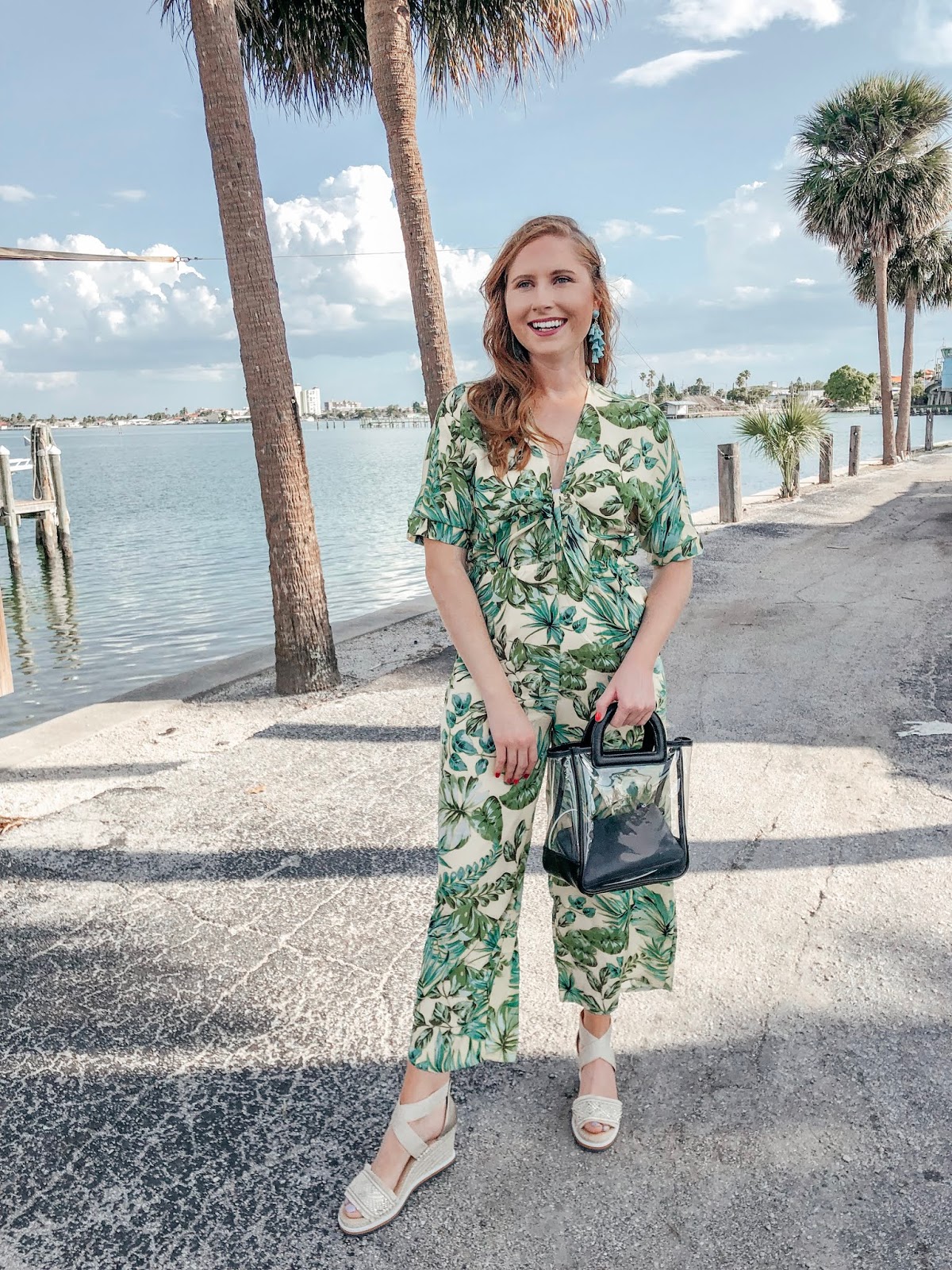 tampa blogger affordable by amanda wearing a yellow and green palm print jumpsuit from bealls outlet. she is walking in front of the starlite cruise ship. she is holding a clear bag from Target and wearing platform tommy hilfiger espadrilles from bealls outlet. 