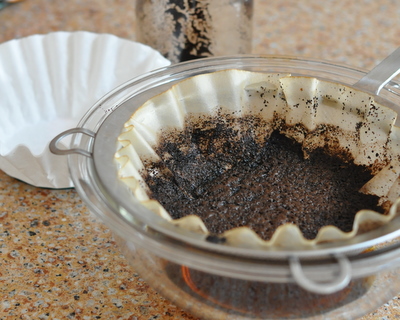Straining coffee grounds for Cold-Brewed Coffee ♥ KitchenParade.com for smooth, low-acidity coffee, just brew coffee grounds in water overnight, then make iced coffee, hot coffee and even coffee smoothies. It's a summer saver!