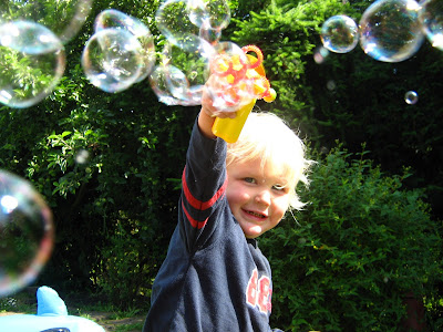 boy with long blond hair having fun with bubbles outside