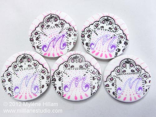 Mint patties decorated with filigree pattern and filled in with monogram "M" in purple and pink.