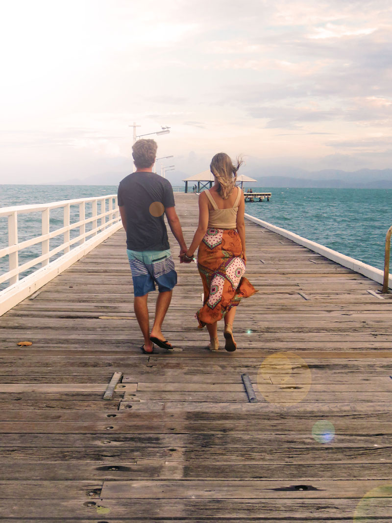 couple walking along pier hand in hand couple walking along pier hand in hand