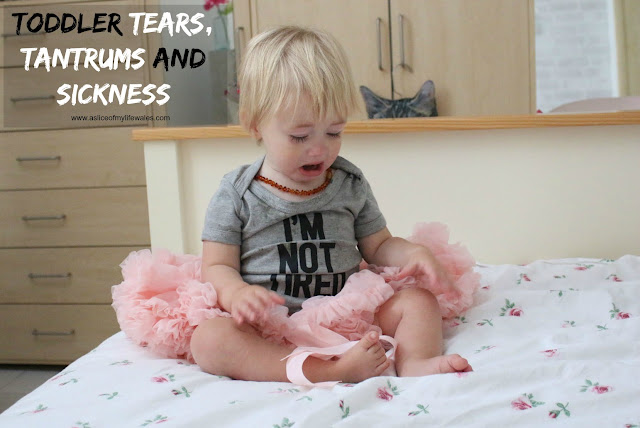 toddler tears tantrums and sickness. crying baby sat on bed wearing i'm not tired vest and pink tutu