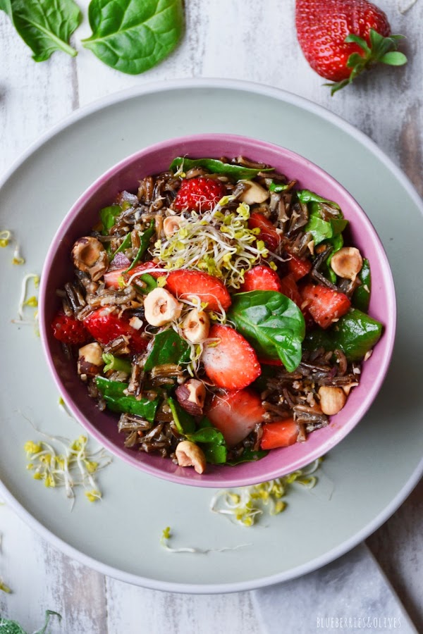 PLANO CENITAL ENSALADA DE ARROZ SALVAJE EN BOL ROSA, PLATO VERDE, FONDO BLANCO Y TRAPO VERDE, HOJAS DE ESPINACA Y FRESAS