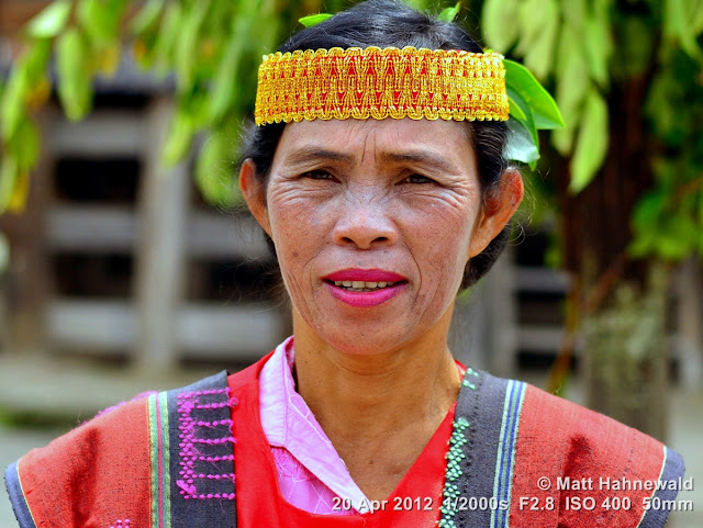 Close-up street portrait (outdoor headshot) of a Toba Batak dancer wearing a handwoven ulos draped over her shoulders (the traditional Batak costume); Simanindo, Samosir Island, Lake Toba, Sumatra, Indonesia. people, portrait, street portrait, headshot, Indonesia, Sumatra, Lake Toba, Samosir Island, Batak women, folk dancer, traditional Batak dance, simanindo