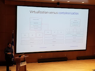 Picture of Adrian on the stage talking about the difference between VMs and containers.