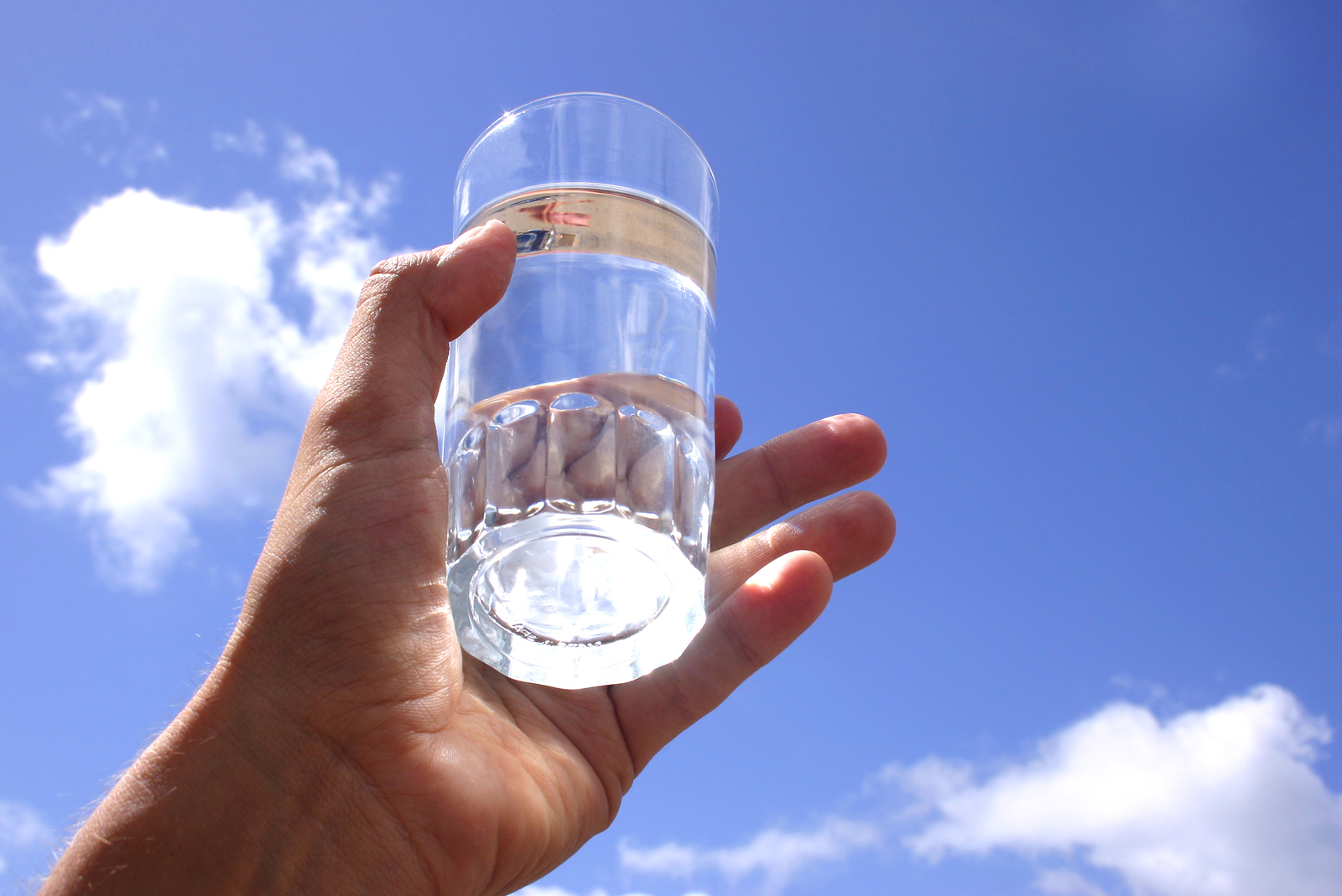 Отпуск питьевой воды. Стакан воды в руке. Стакан в руке. Полный стакан воды. Чистая вода.