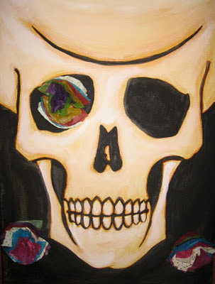 A custom painting of a skull created for a Day of the Dead shrine.  Paper flowers have been attached to the canvas and show a grinning skull in honor of relatives and those who have passed on.
