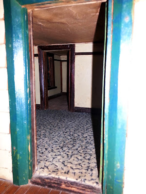 Inside view of a 1930s vintage dolls' house bungalow through the back door, showing the kitchen.