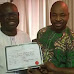 Rep-elect presents Certificate of Return to MC Oluomo