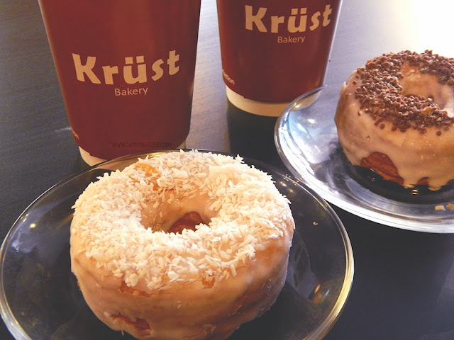two cronuts on plates with coffee in the background