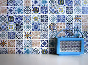 Modern one-twelfth scale miniature radio in front of a wall of random tiles in shades of blue.