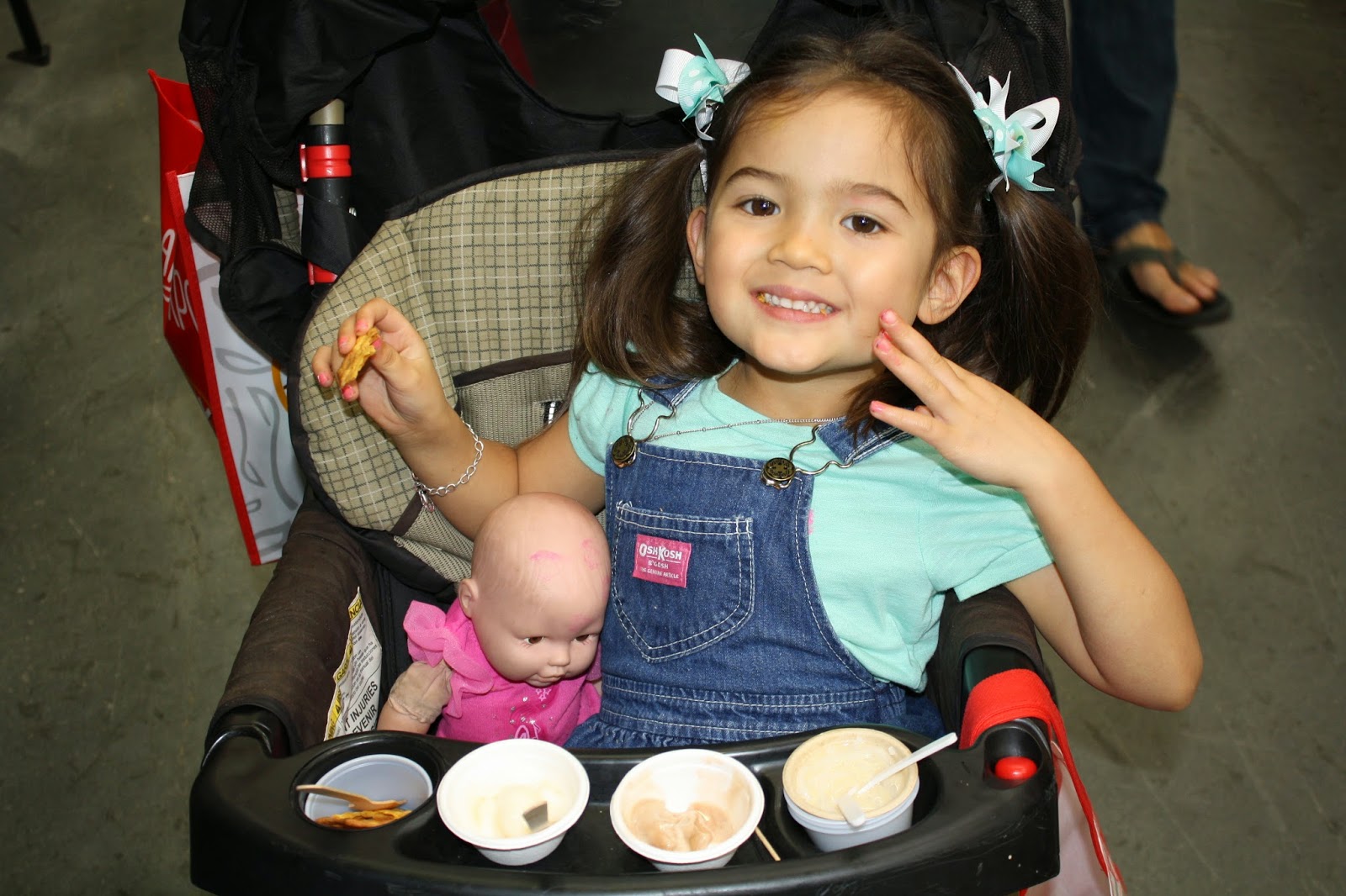 little girl in stroller with baby doll enjoying samples at the Gluten-Free & Allergy-Friendly Expo 