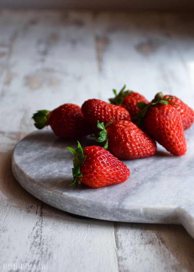 FRESAS SOBRE TABLA DE MÁRMOL, FONDO BLANCO Y LUZ TENUE