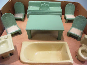 Set of metal dolls' house bathroom and kitchen furniture displayed in its box.