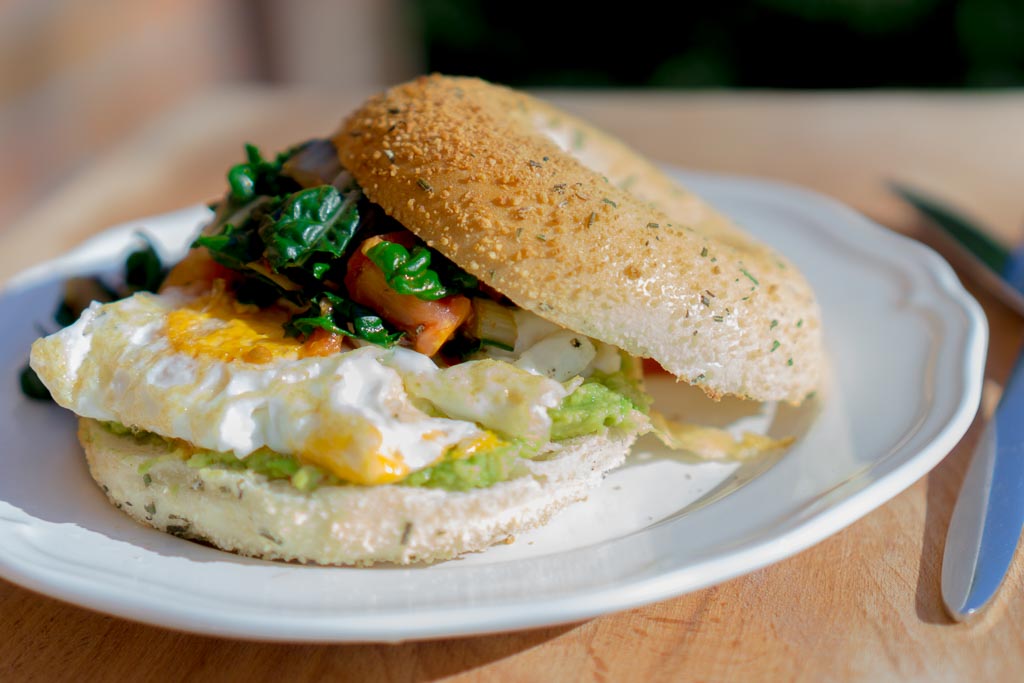 A garlic & rosemary bagel from Huff Bagelry served up with some avocado, sunny side up egg (in all its yolky glory!) and a side of flash fried silver beet and tomatoes in coconut oil and chilli. | in happenstance