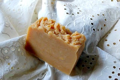A bar of caramel-colored handmade soap on a lacy cloth.