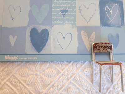 Green tissue box cover with a blue and white heart print with a one-twelfth scale shabby white chair below it.