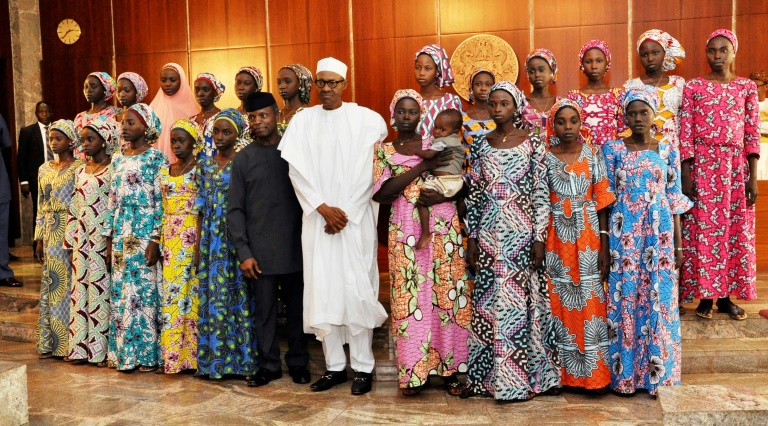 Nigerian President Muhammadu Buhari (C) poses at State House in Abuja on October 19, 2016 with the 21 Chibok girls who were released by Boko Haram the previous week
