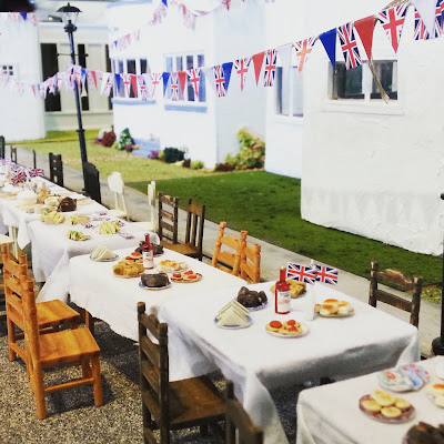 Miniature scene of a VE Day street party in front of a row of Art Deco houses.