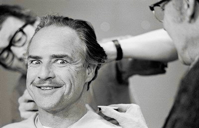 Marlon Brando making a funny face while having makeup applied for his role in The Godfather movieloversreviews.filminspector.com